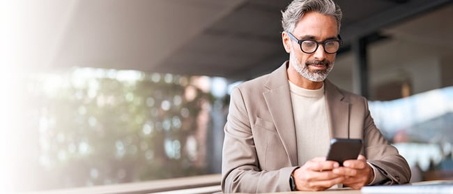 A professional reviews information on his smartphone in a modern workspace, reflecting a moment of pause and decision‑making during an AI implementation.