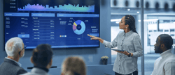 female-executive-presents-performance-data-on-digital-monitor-to-leadership-team