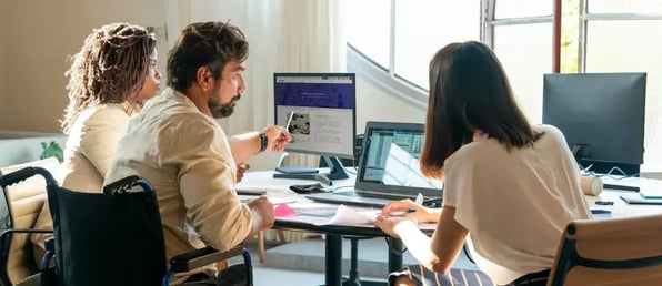 Three people in an office working on computers