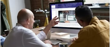 Two colleagues discuss a chart looking at a computer monitor