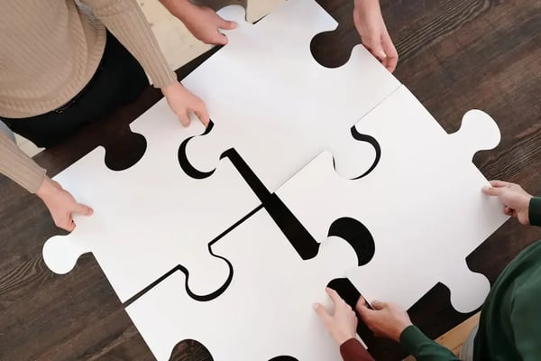 Large puzzle pieces on a table being brought together