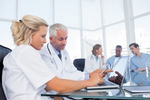 Doctors using a laptop in a bright office