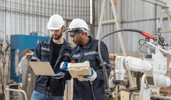 Factory technicians leveraging digital systems for robotic operations in manufacturing.