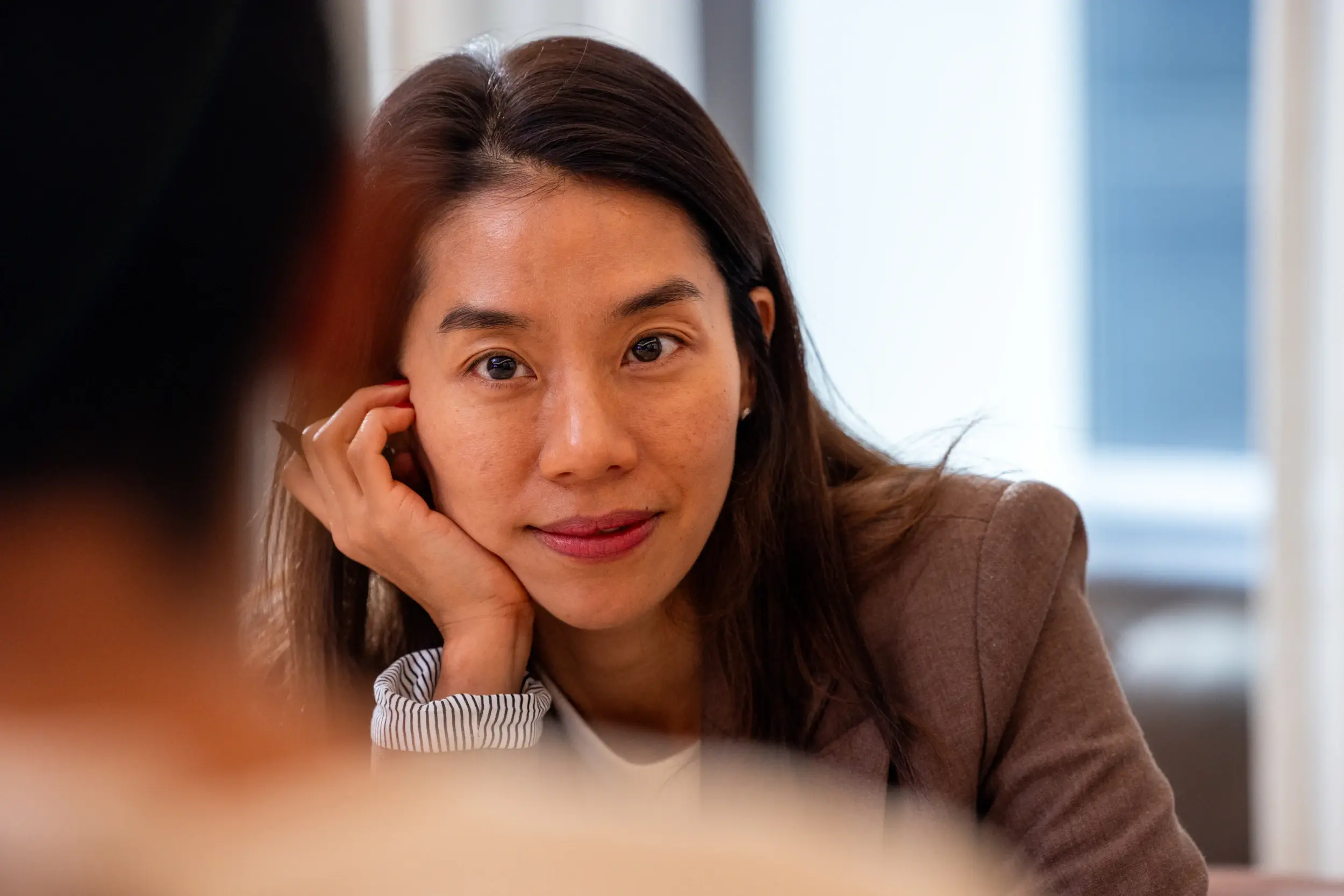 Woman resting her head on her hand and listening during a meeting.