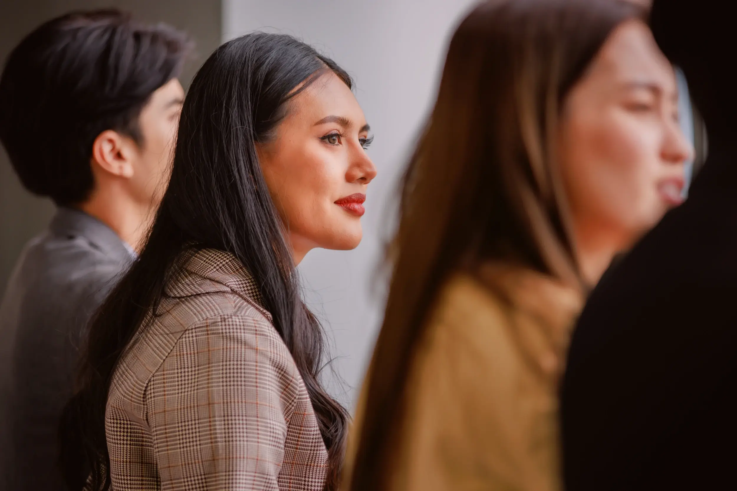 Woman in a plaid blazer listening attentively during a meeting.