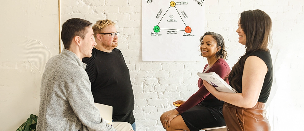A group of people discussing change management with a PCT depicted on a poster behind them.